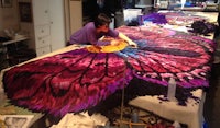 a woman is working on a large piece of fabric