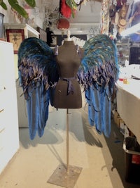 blue feathered wings on a mannequin in a workshop