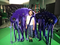 a woman standing next to a giant purple jellyfish